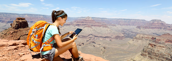 Chica consultando tablet mientras descansa en la montaña