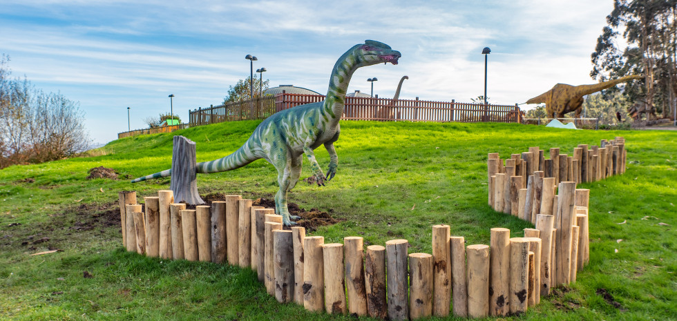 Reproducción del dinosaurio Liliensternus en el jardín exterior del Museo del Jurásico de Asturias. Es un dinosaurio terópodo (carnívoro) con un patrón de manchas de color verde, esbelto y con cresta. En la boca tiene un pedazo de carne.